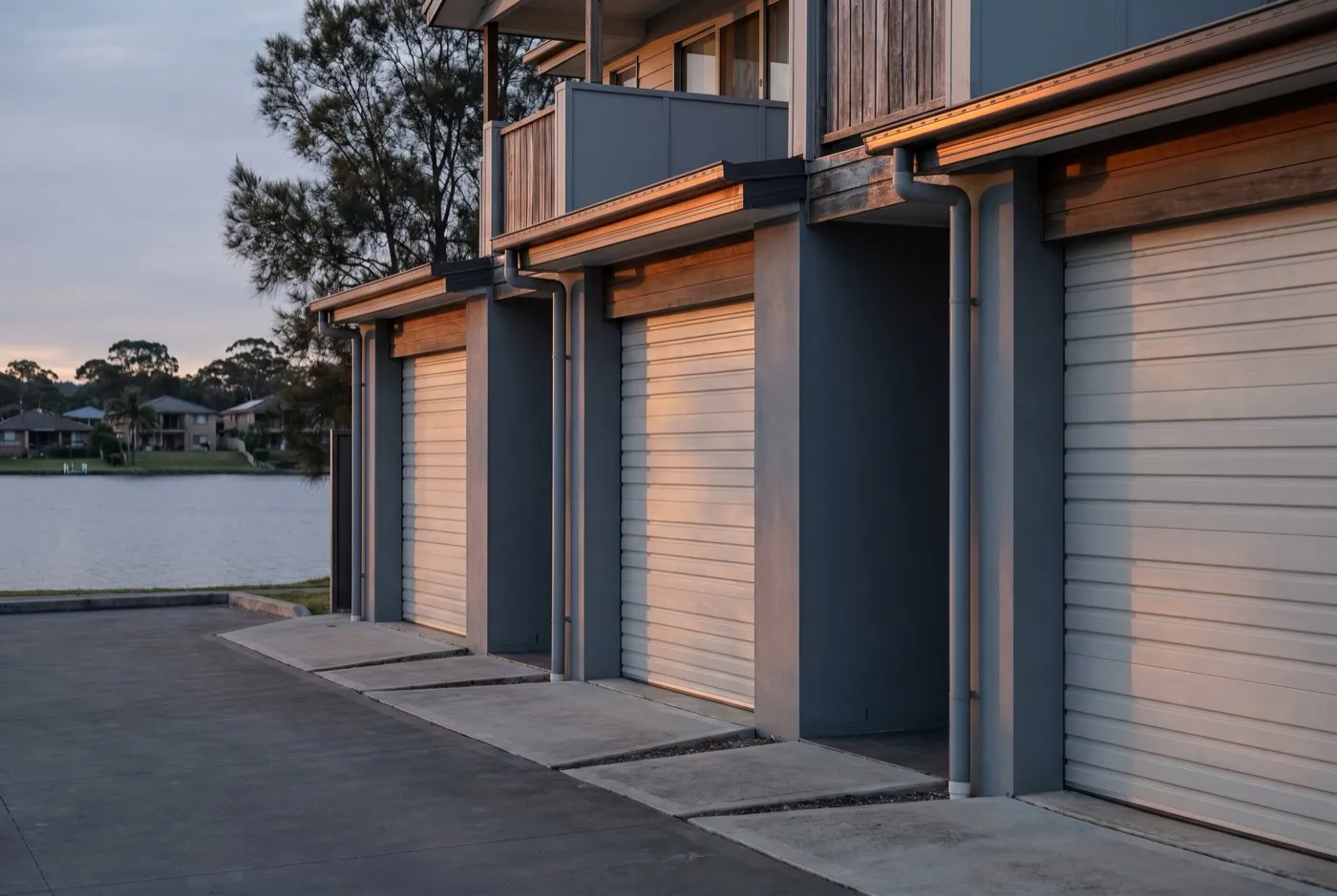 Three townhouse garages side by side with roller doors and close-set rendered walls